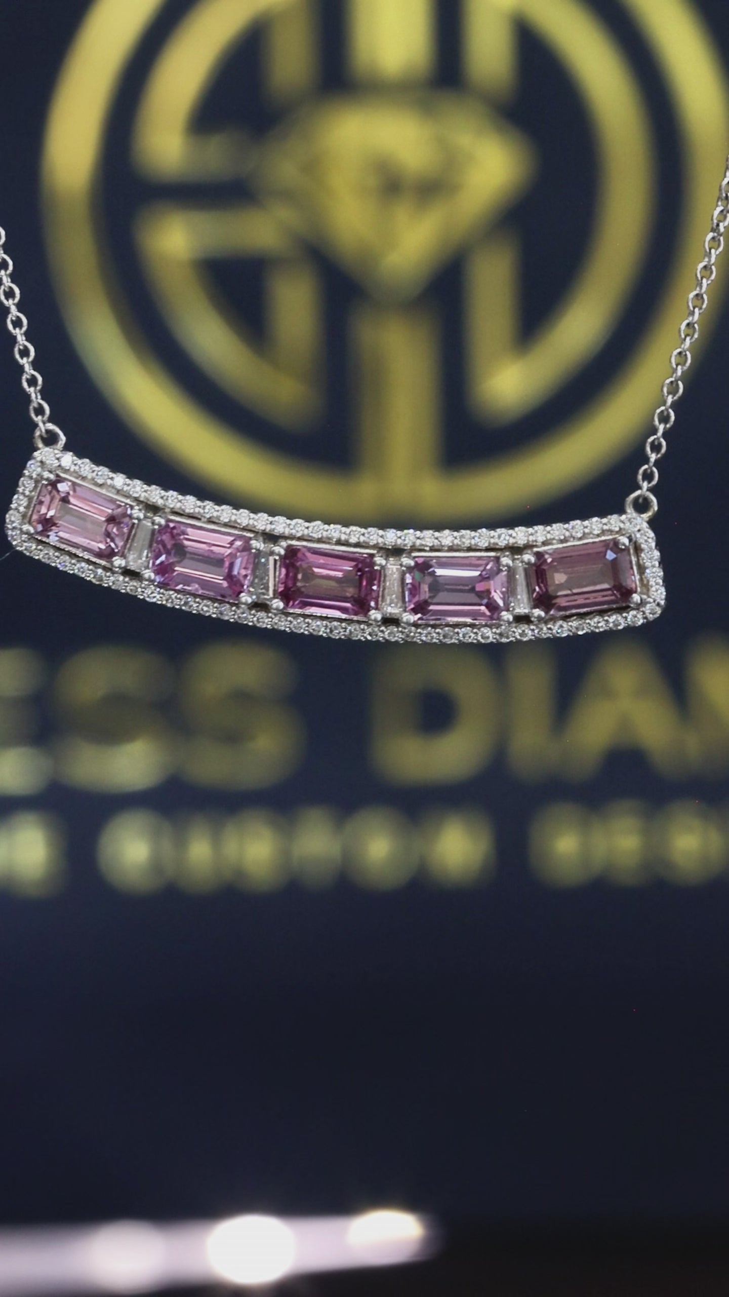 14K white gold curved pink sapphire bar necklace with 2.9 carat emerald cut sapphires and 0.5 carat diamond halo setting